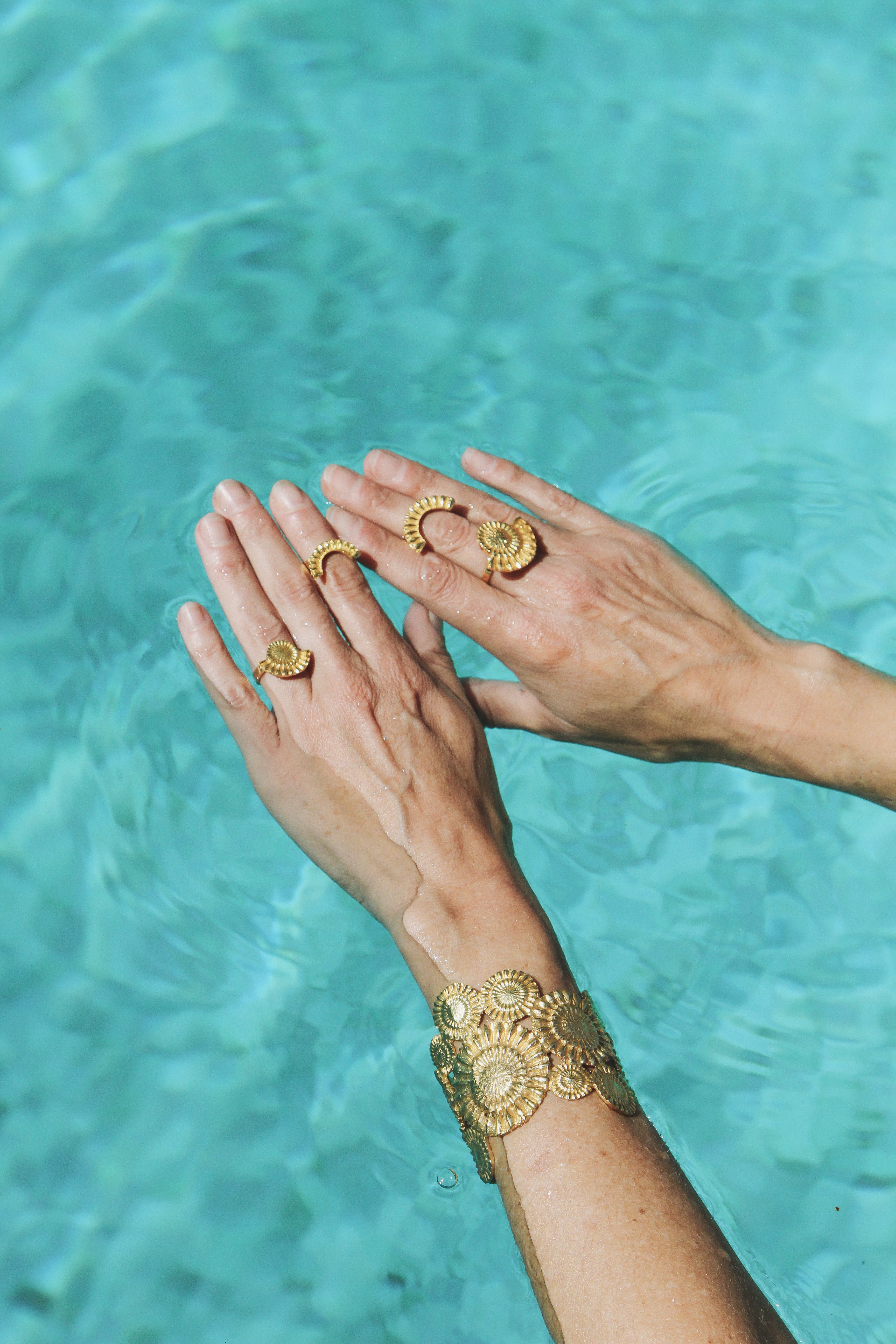 hands in pool wearing sophie simone designs rings and bracelet